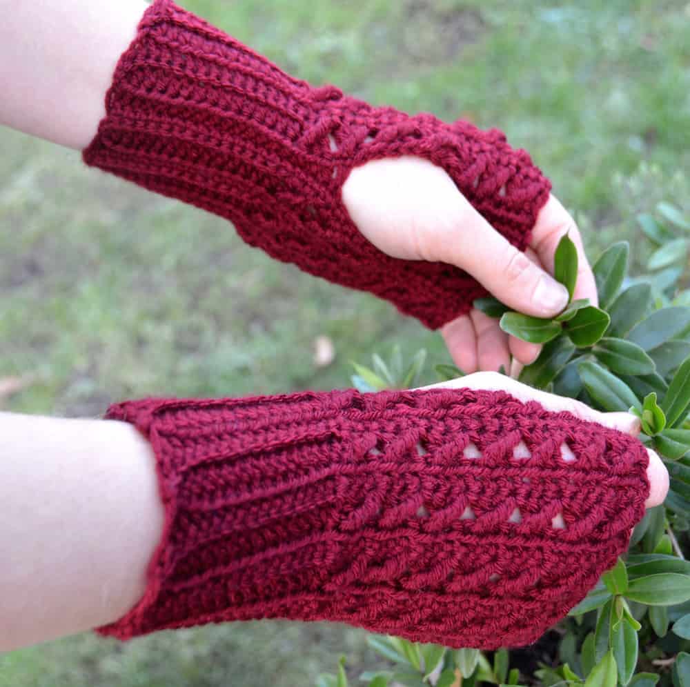 hands wearing fingerless crochet mittens holding plant leaves