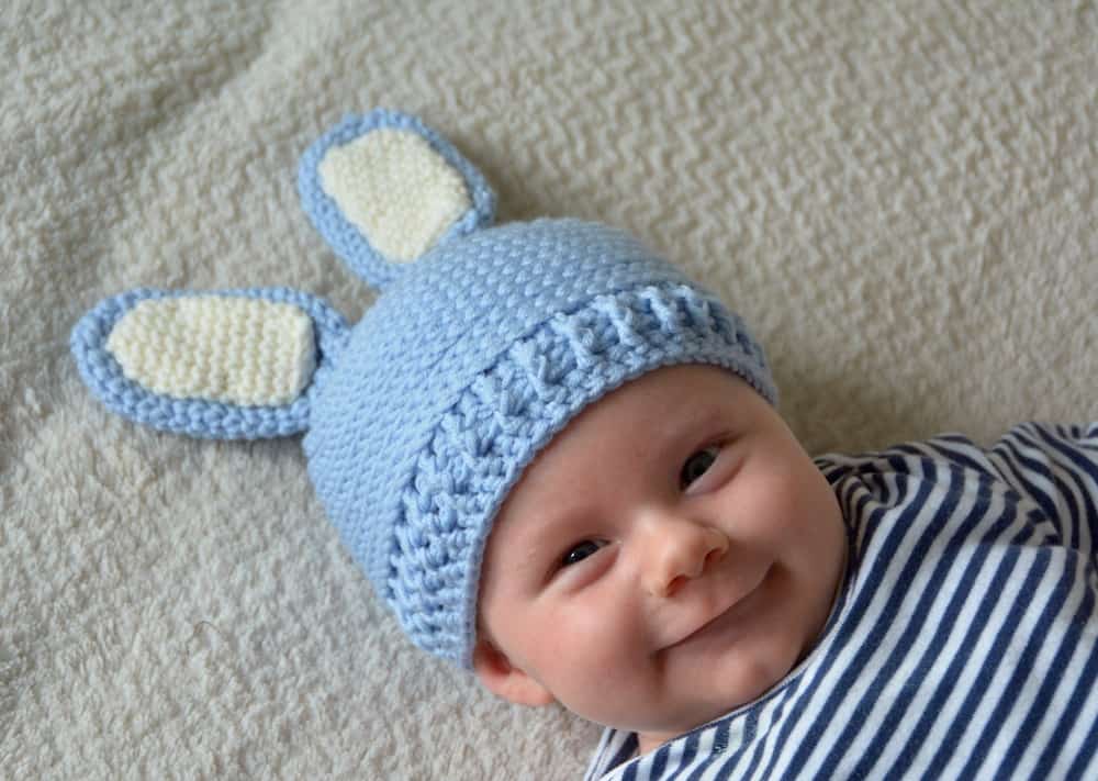 smiling baby wearing crochet baby bunny hat with floppy ears