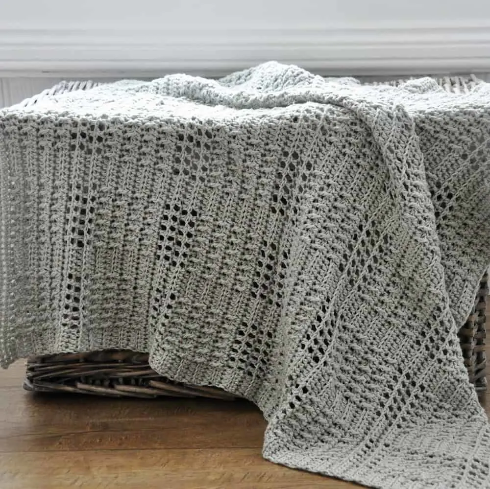 a crocheted lacy baby blanket in silver colour