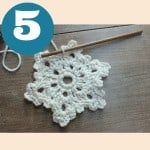 A crocheted snowflake pattern on a wooden table.