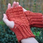 A beginner showcasing a crocheted pattern of fingerless mitts.