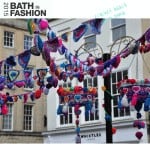 A group of patterned crocheted hearts hanging on a street.