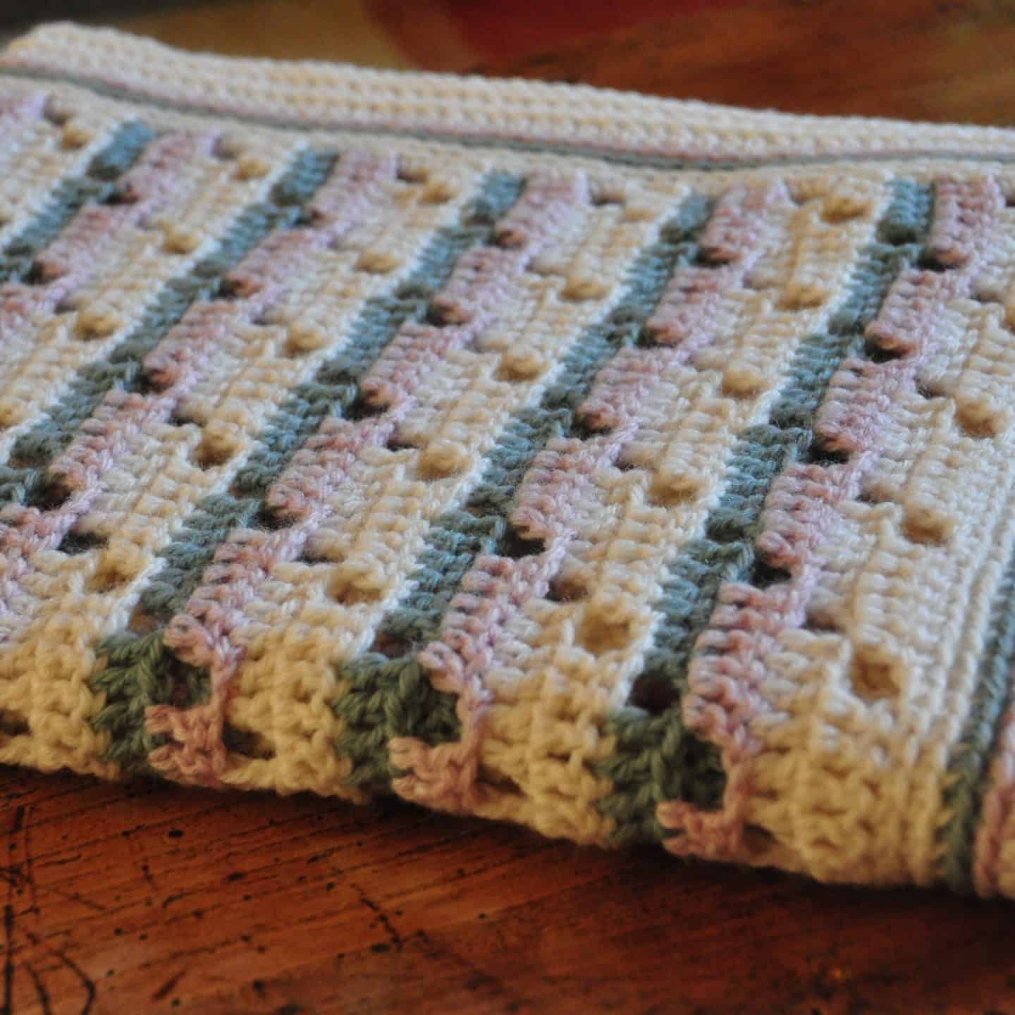 Learn to crochet this soft and subtle baby blanket as the perfect gift for a new arrival. Including a free crochet pattern and stitch tutorial anyone, even beginners, can master this filet crochet technique.