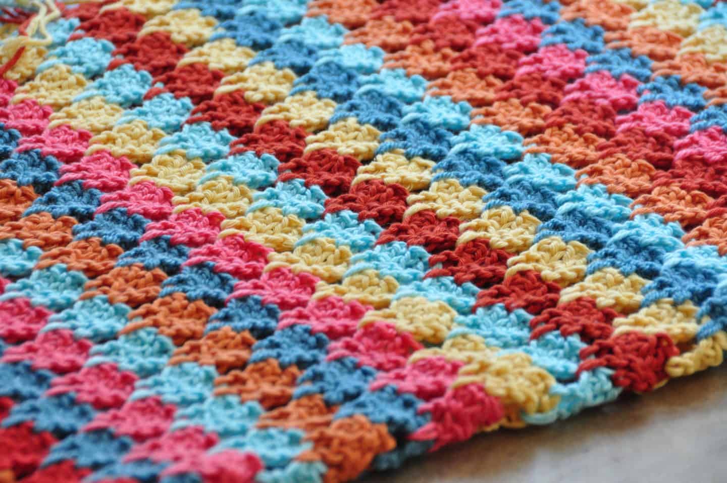 Tackle your yarn stash and learn how to crochet the larksfoot stitch with this beautiful and easy free crochet blanket pattern. With step by step photos and entire crochet pattern, the larksfoot makes the perfect baby blanket, home throw, scarf or garment that is great for a beginner.