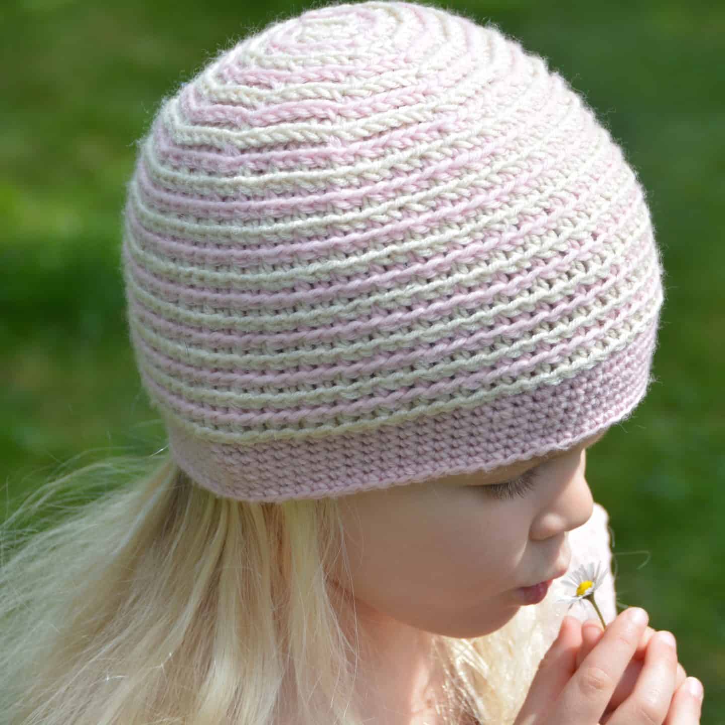 girl wearing pink and cream stripe crochet beanie hat for beginners