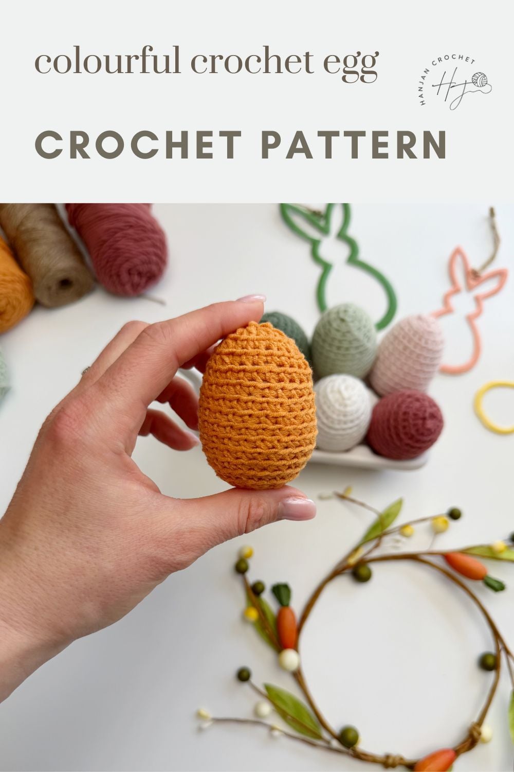 A hand holds a crocheted orange egg; several crochet Easter eggs and yarn are on a table with decorative elements in the background. Text reads "colourful crochet egg CROCHET PATTERN.