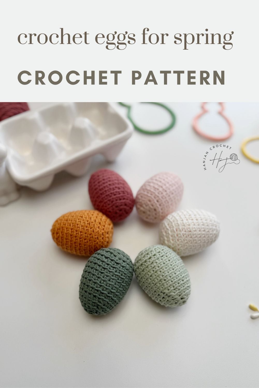 Six crochet Easter eggs in pastel hues are arranged next to a white egg carton on a white surface, with text reading “crochet eggs for spring CROCHET PATTERN.”.