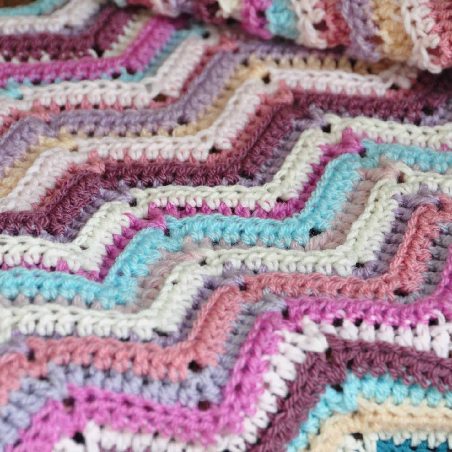 Learn to crochet the ripple stitch with this free crochet tutorial and crochet blanket pattern in both UK and US terms. Feel the retro decor vibe with bright colours or choose classic tones to make your crochet blanket perfect for you. Great for beginner crocheters. 