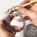 A person using a crochet hook to knit a ring.