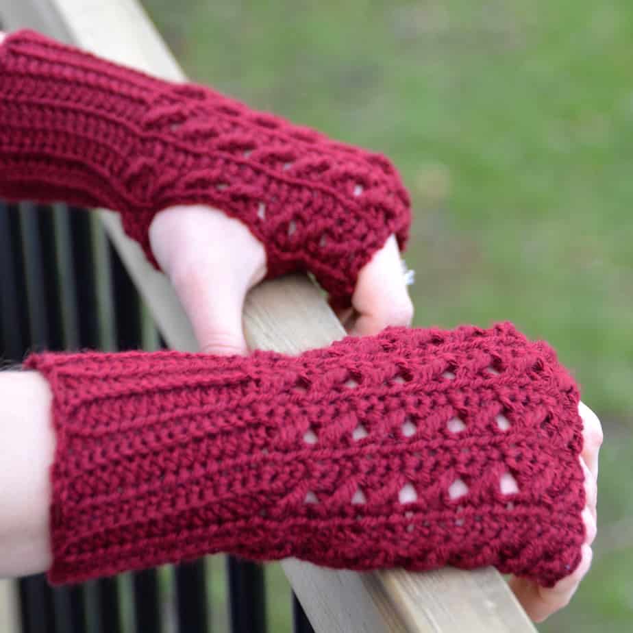 woman holding gate wearing red crochet mittens with textured design 