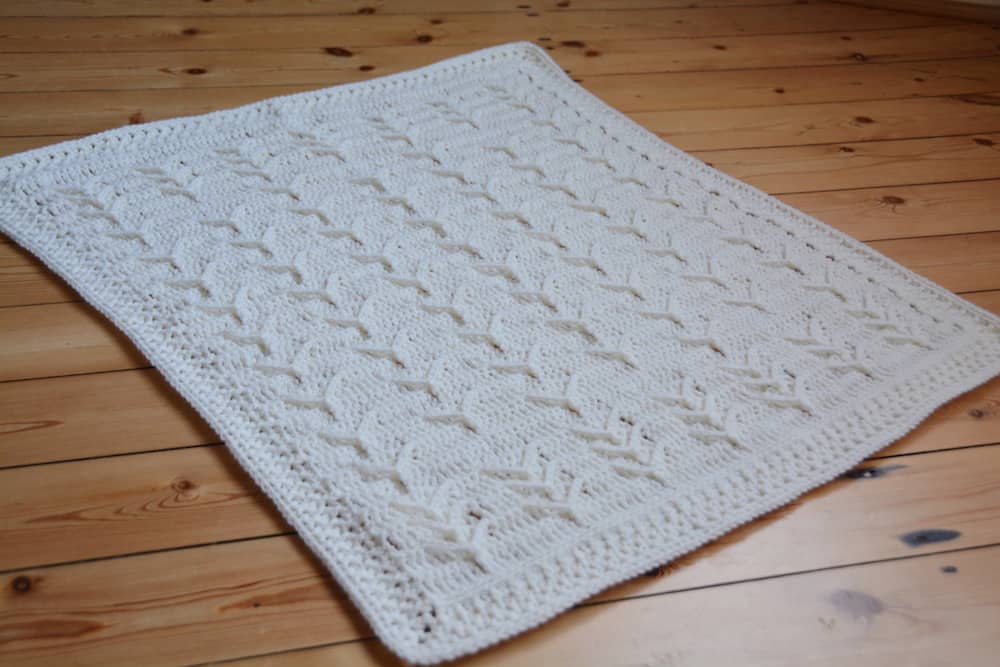 Traditional heirloom crochet baby blanket in cream.