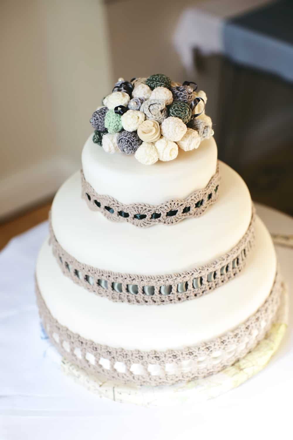 White wedding cake with crochet flower topper and crochet cake collar. 