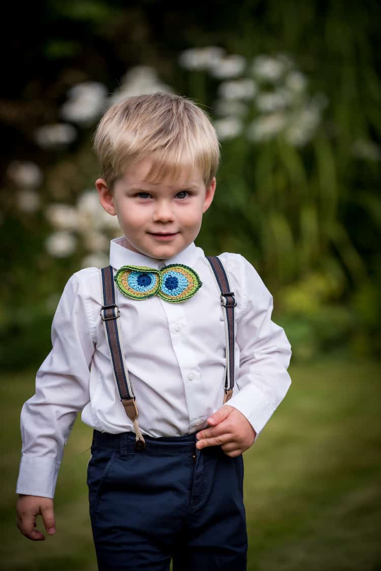 Little boy wearing crochet bow tie in peacock feather colours. 