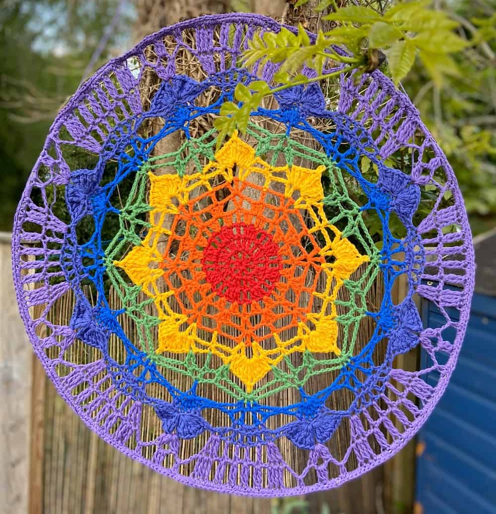 Crochet rainbow mandala hanging pattern by HanJan Crochet. It's the perfect wall hanging or door hanging to give a pop of colour and energy to your home. A free crochet mandala pattern for everyone to enjoy.
