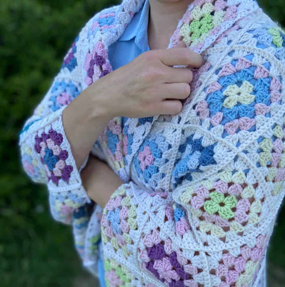 Woman with granny square blanket wrapped around her.