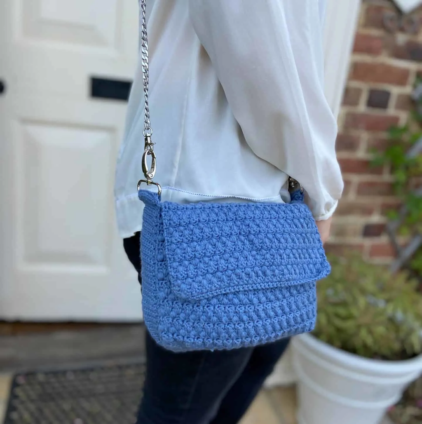 Woman wearing blue crochet shoulder bag.