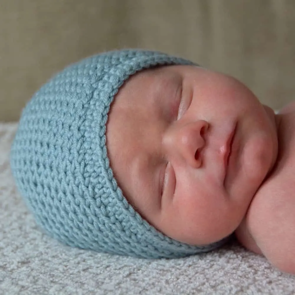 newborn baby asleep wearing a quick crochet baby hat 