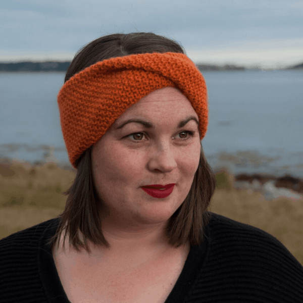 woman looking sideways wearing orange twisted crochet headband