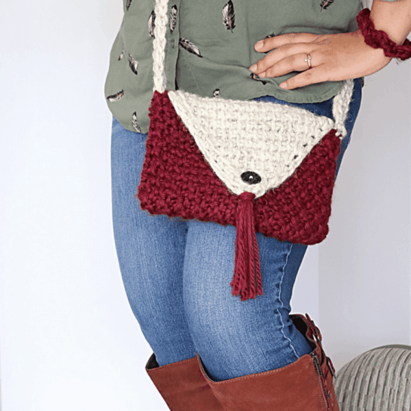 woman in boots with hands on hips wearing red and cream crochet headband with tassel