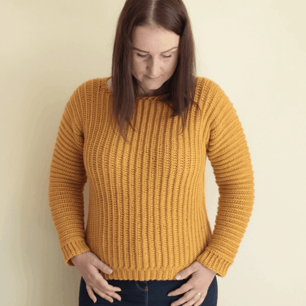 woman against white background wearing mustard yellow crochet jumper 