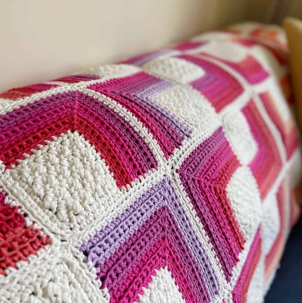 lilac, purple, pink and white sqaure motif crochet blanket on back of sofa