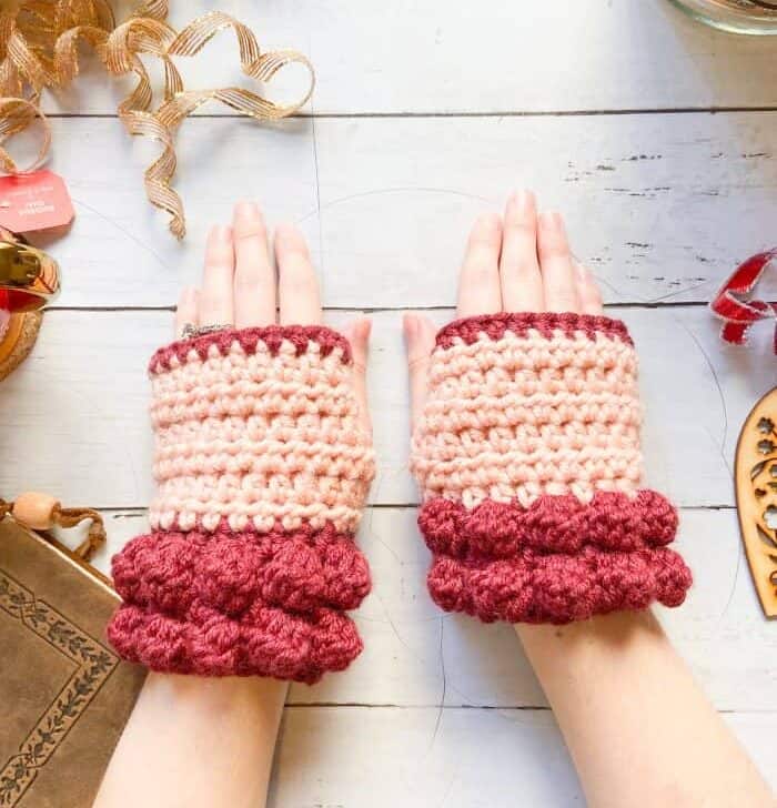 woman wearing red and peach chunky crochet fingerless gloves with white background
