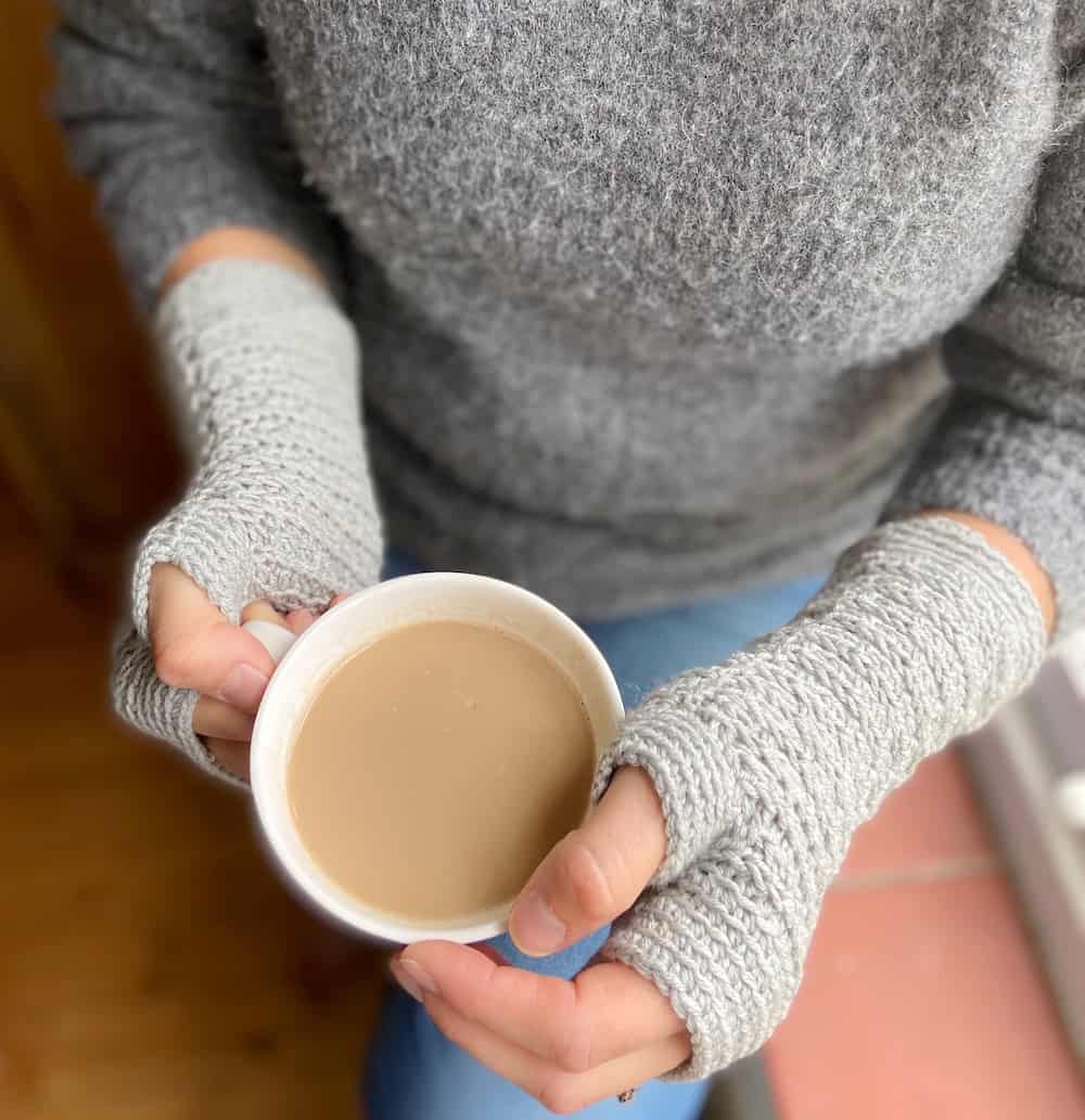 Overhead view of woman holding coffee cup wearing easy crochet gloves.