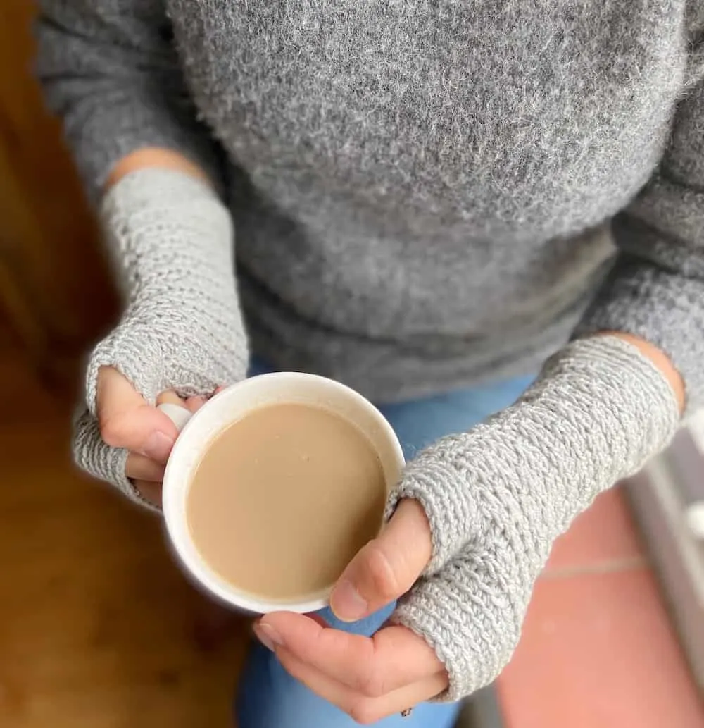 Overhead view of woman holding coffee cup wearing easy crochet gloves.