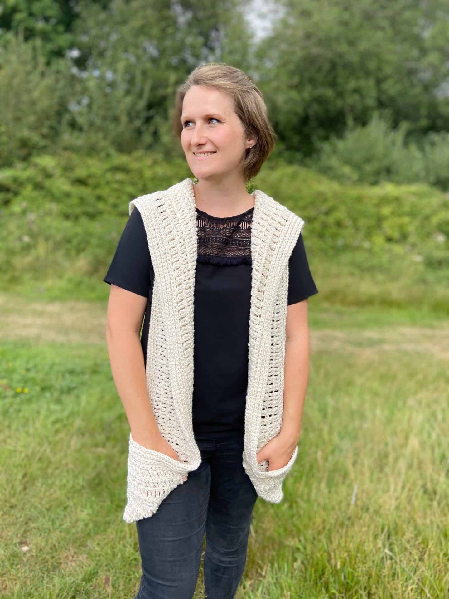 woman in field wearing hooded cream crochet pocket shawl