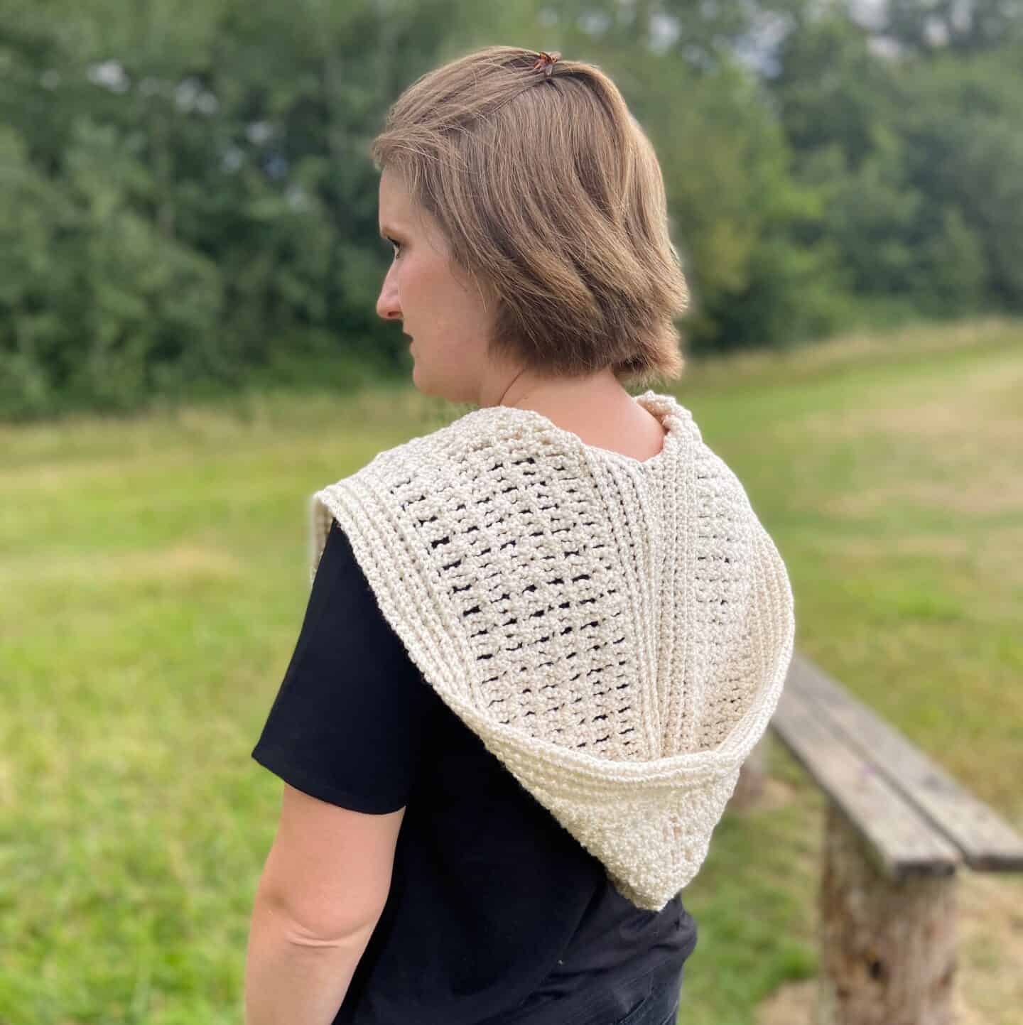 woman in field wearing hooded crochet scarf