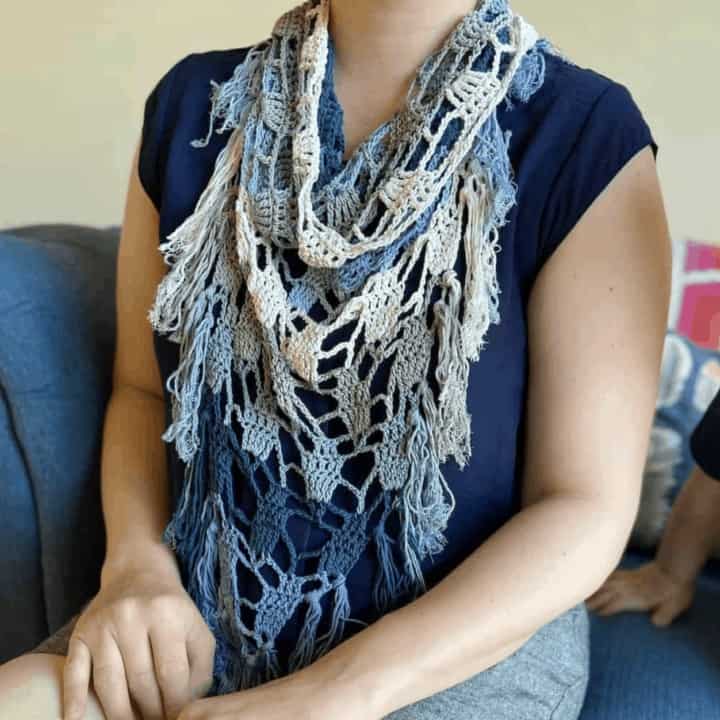 woman sitting on sofa wearing blue, green and grey crochet bandana scarf