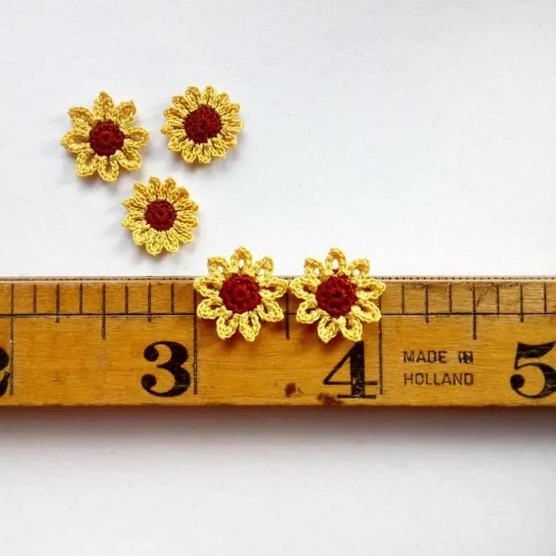 5 tiny micro crochet sunflowers on a vintage ruler