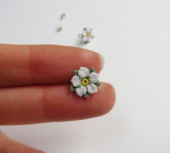 tiny micro crochet white rose flower held on two fingers