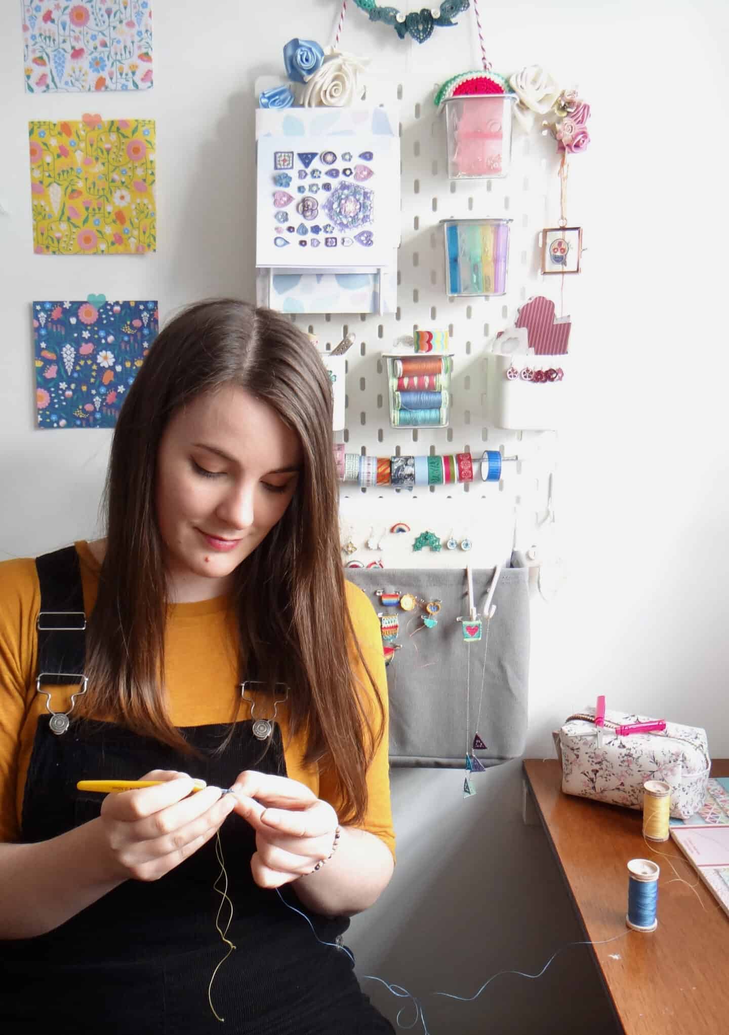 Micro crochet designer Steffi Glaves sitting at desk crocheting a tiny flower