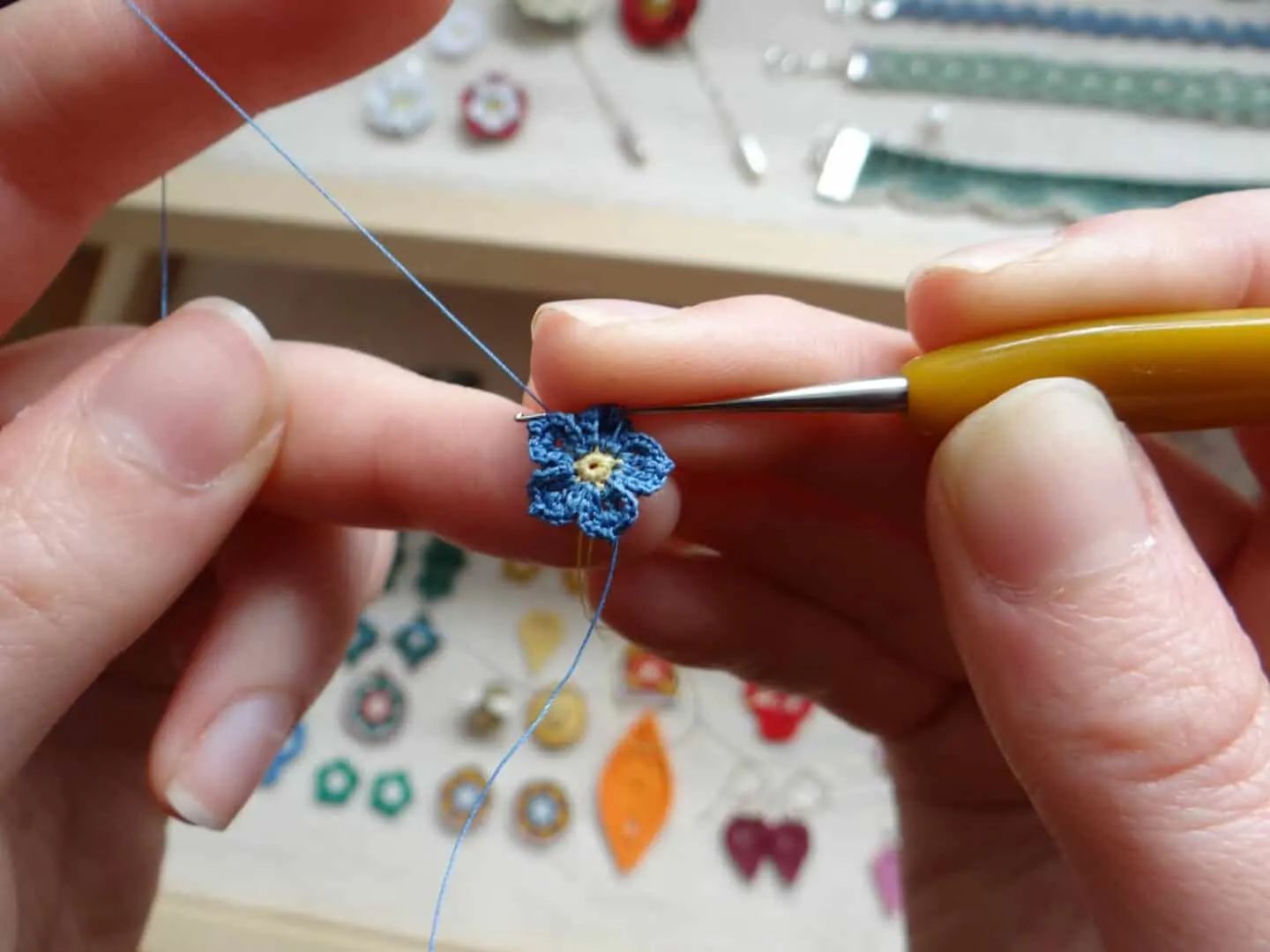 tiny micro crochet forget me not flower being crocheted with hook in hands