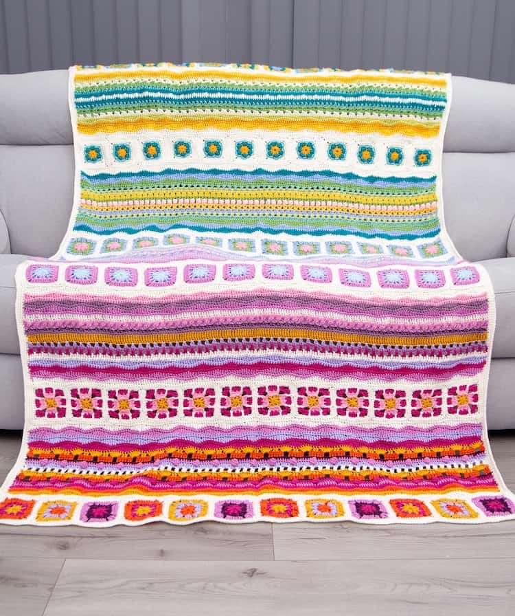 bright and colourful crochet blanket laying across grey sofa