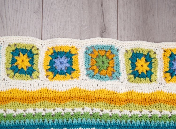 crochet blanket granny squares in bright yellow, blues and greens with white border