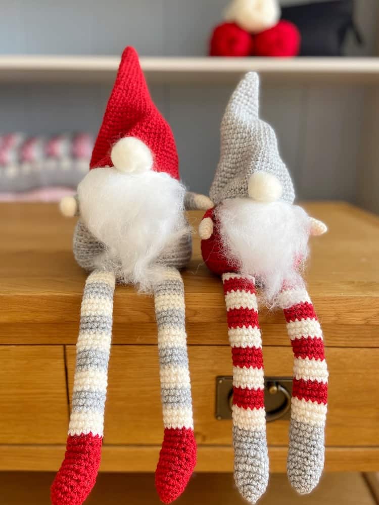 Pair of red, white and grey Christmas crochet gnomes sitting on a table