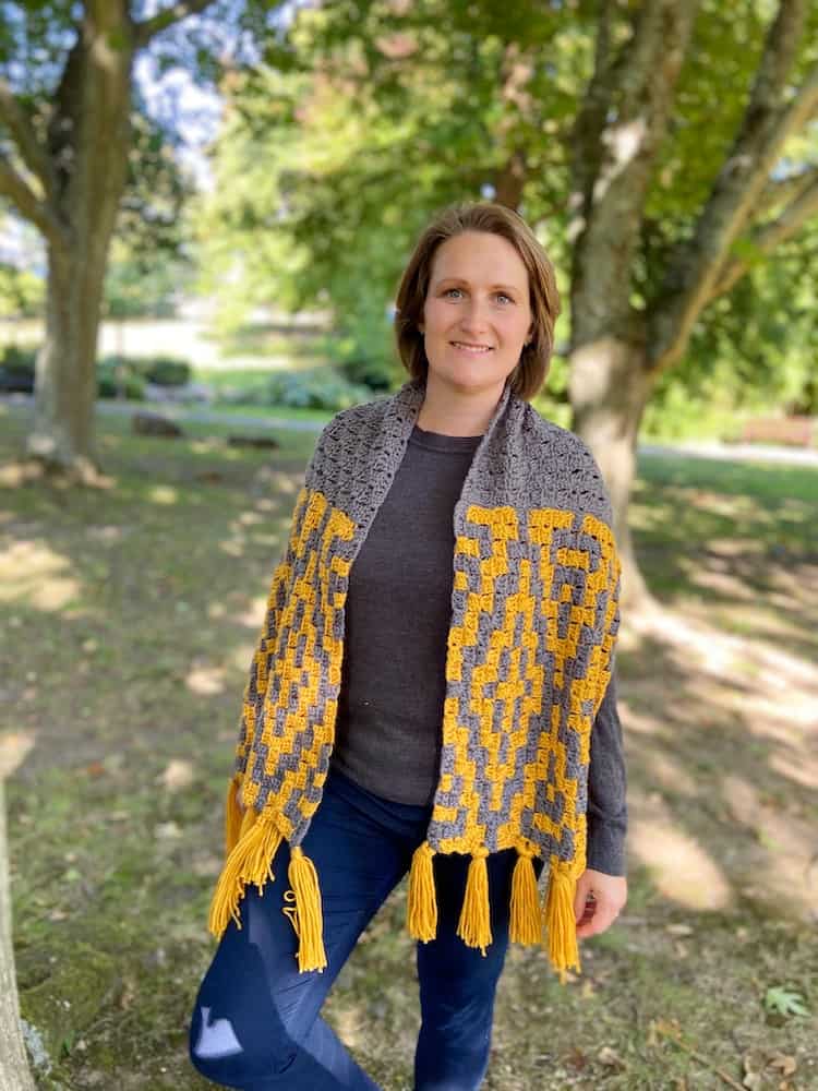 woman smiling wearing grey and yellow corner to corner crochet scarf wrapped around her shoulders