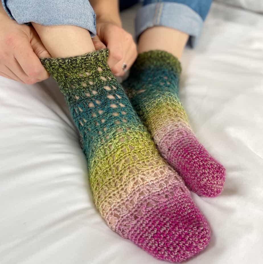 woman putting multicoloured lacy crochet socks on