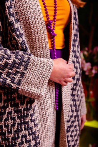 Woman wearing purple and cream mosaic crochet cardigan.