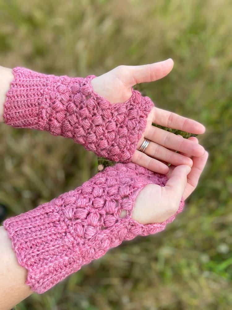 close up of hands holding palms open wearing pink puff stitch crochet mittens 