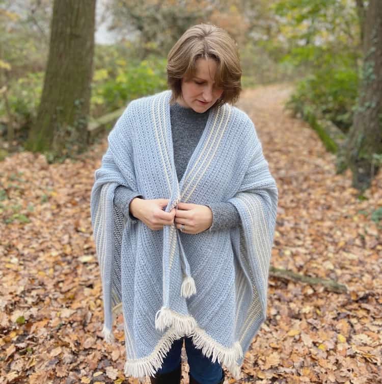 Woman in woodland wearing crochet ruana with fringe.