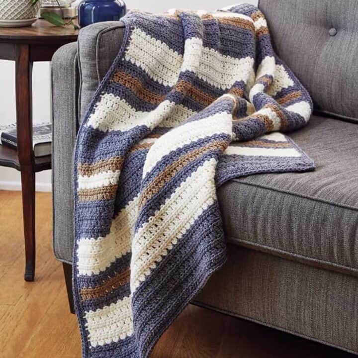 Blue and white crocheted throw with stripes.