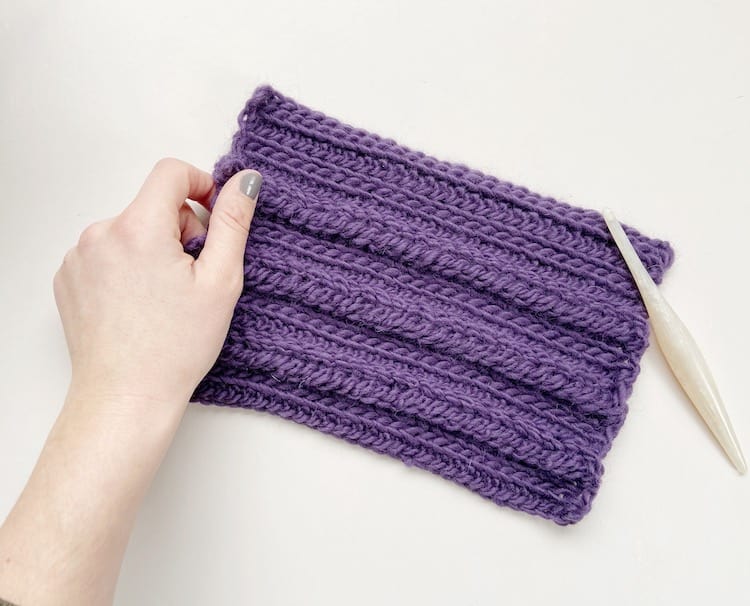 hand holding crochet braid stitch swatch in purple yarn