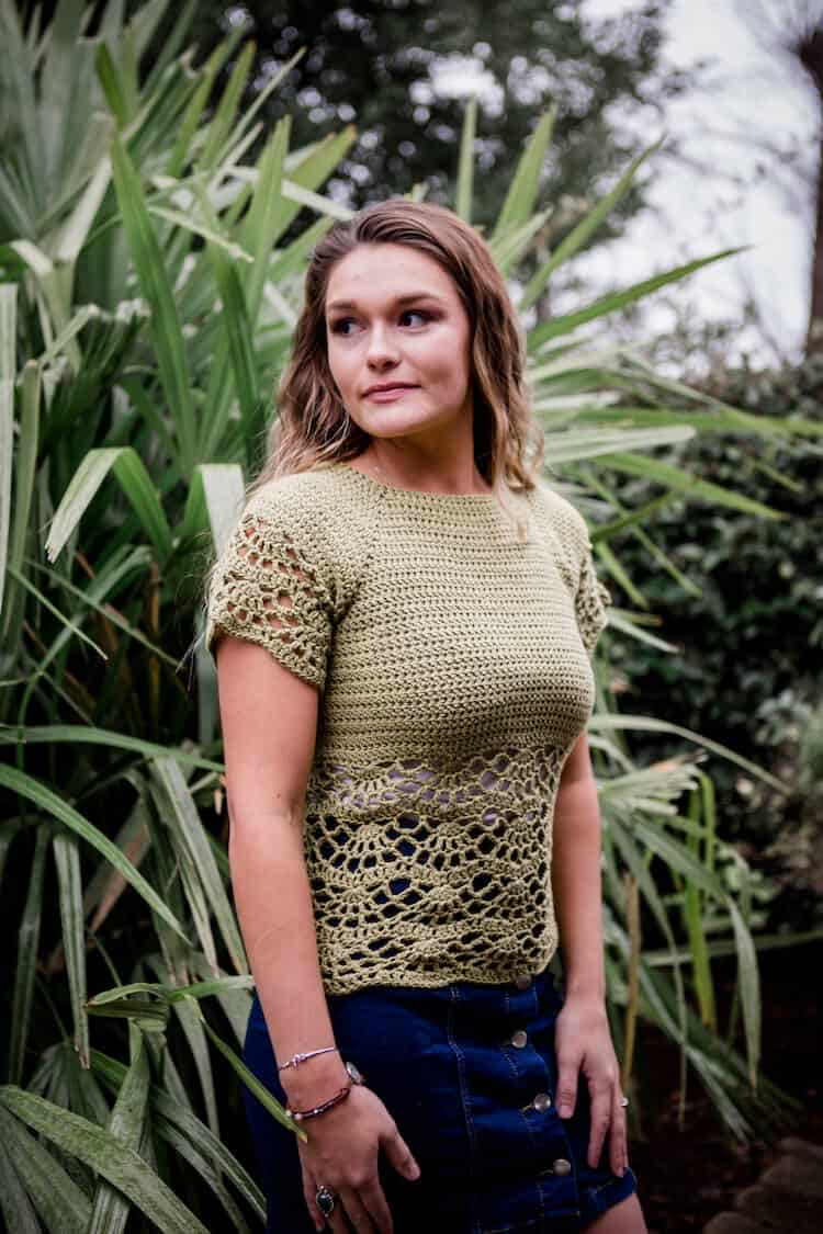 woman with long hair looking sideways wearing green lace crochet short sleeved top