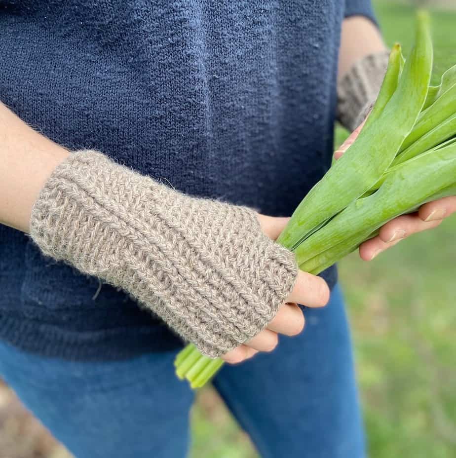 close up of textured crochet hand warmers on woman in jeans holding bunch of tulips