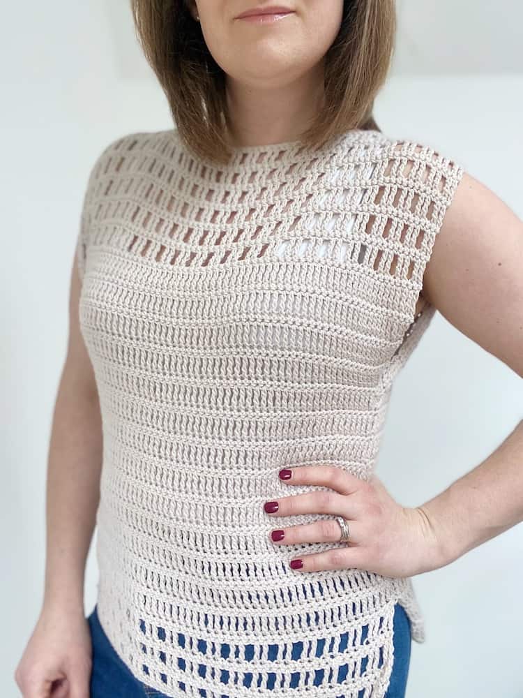 Woman with one hand on hip wearing cream easy crochet top pattern.