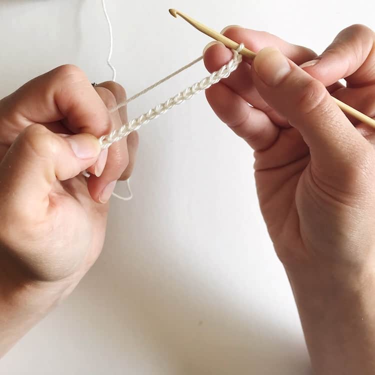 Two hands holding white crochet chain.