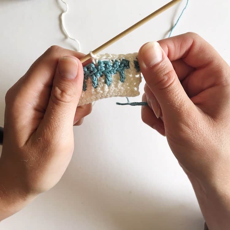 Two hands crocheting a white row.